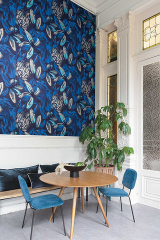 Dining room with blue floral wallpaper, wooden table, and blue chairs.
