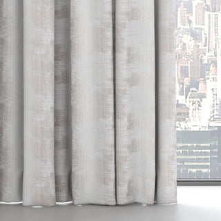 Constellation Collection drapery fabric featuring floor-length light grey and beige marbled curtains with soft vertical folds, framed beside a large window overlooking a blurred cityscape background.