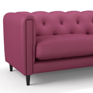 Soho Collection upholstery fabric featuring a classic tufted Chesterfield sofa in a vibrant magenta pink, styled with rolled arms and sleek black wooden legs against a clean white background.
