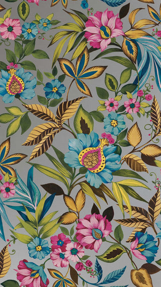 Crown Bali Tropical Raya wallpaper featuring a vibrant botanical floral design. Lush tropical blooms in vibrant pink, turquoise blue, and yellow with rich gold and green foliage weave across a grey background for a bold statement.