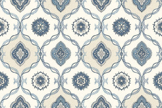 A close-up view of the Avignon wallpaper swatch from the Crown Provence collection. The pattern features a classic ogee trellis layout, formed by delicate, interlocking leafy vine borders in blues. Alternating compartments enclose intricate, circular floral mandalas and ornate, four-lobed medallion motifs. The elegant, symmetrical design is set against a warm cream background enhanced by a subtle linen-textured faux weave, creating a timeless and sophisticated aesthetic.