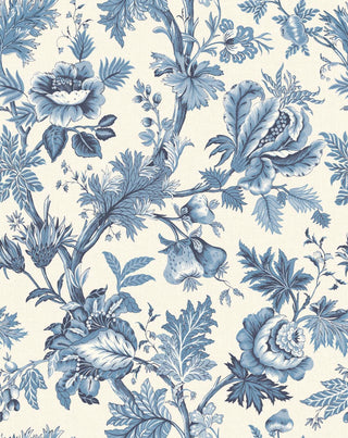 A close-up view of the Cabris wallpaper swatch from the Crown Provence collection. The pattern is a classic French Toile de Jouy, featuring winding botanical branches, large ornate blossoms, detailed leaves, and hanging pomegranates or figs. The entirely monochromatic design is rendered in shades of timeless denim and cornflower blue, standing out against a crisp cream background. The backdrop features a subtle linen-textured faux weave, giving this elegant print a warm, high-end fabric-like depth.