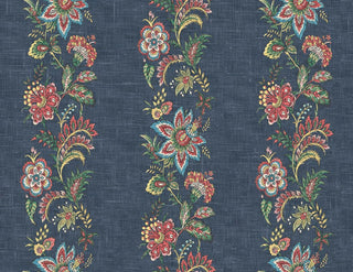 A close-up view of the Callas wallpaper swatch from the Crown Provence collection. The design features rich, vertical trails of intricate botanical florals, vines, and ornate blossoms in deep red, soft pink, teal, and sage green tones. These vibrant, folk-inspired floral stripes repeat gracefully across a dark denim blue background. The backdrop is enhanced with a tactile, linen-look faux weave texture that gives the pattern a warm, high-end fabric appearance, blending rustic charm with elegant detail.