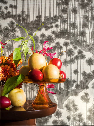Decorative display of fruits and flowers on a stand with a patterned wallpaper background