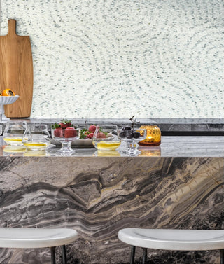 Modern kitchen with marble countertop, fruit display, and cutting board.