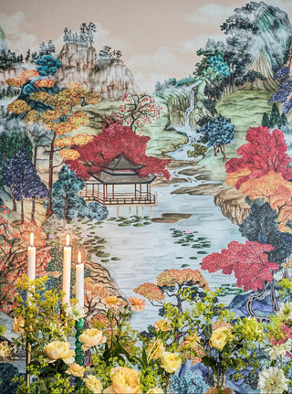 Decorative tapestry with a scenic landscape featuring trees, a pagoda, and flowers.