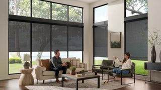 Living room with large windows and Alta roller shades, people sitting on a couch.