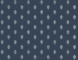 A close-up view of the Sault wallpaper swatch from the Crown Provence collection. The pattern features a small, intricate repeating damask or fleur-de-lis inspired motif in a crisp white color. The motifs are arranged in a neat, staggered half-drop layout across a deep navy blue background. The backdrop has a subtle, linen-look texture with fine horizontal faux-weave lines that add depth and a fabric-like quality to the design. The overall aesthetic is classic, tailored, and traditionally elegant.
