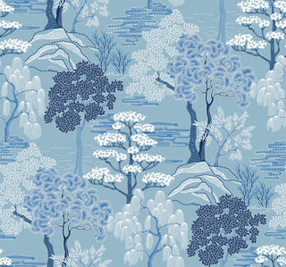 Close-up swatch of Crown's Chinoiserie collection wallpaper in the Mori Trees pattern. This detailed, illustrative design features a blue background filled with a stylized forest scene inspired by traditional woodblock prints. Various species of trees—including weeping willows, pines, and leafy maples—are rendered in a palette of blues, and white. Linear stitching effects define the rolling hills, clouds, and foliage, creating a rich, scenic, and textured landscape.